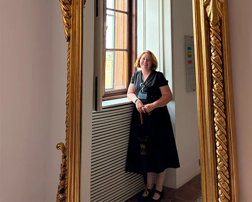 žena u odrazu ogledala nasmješenop stoji ispred prozora